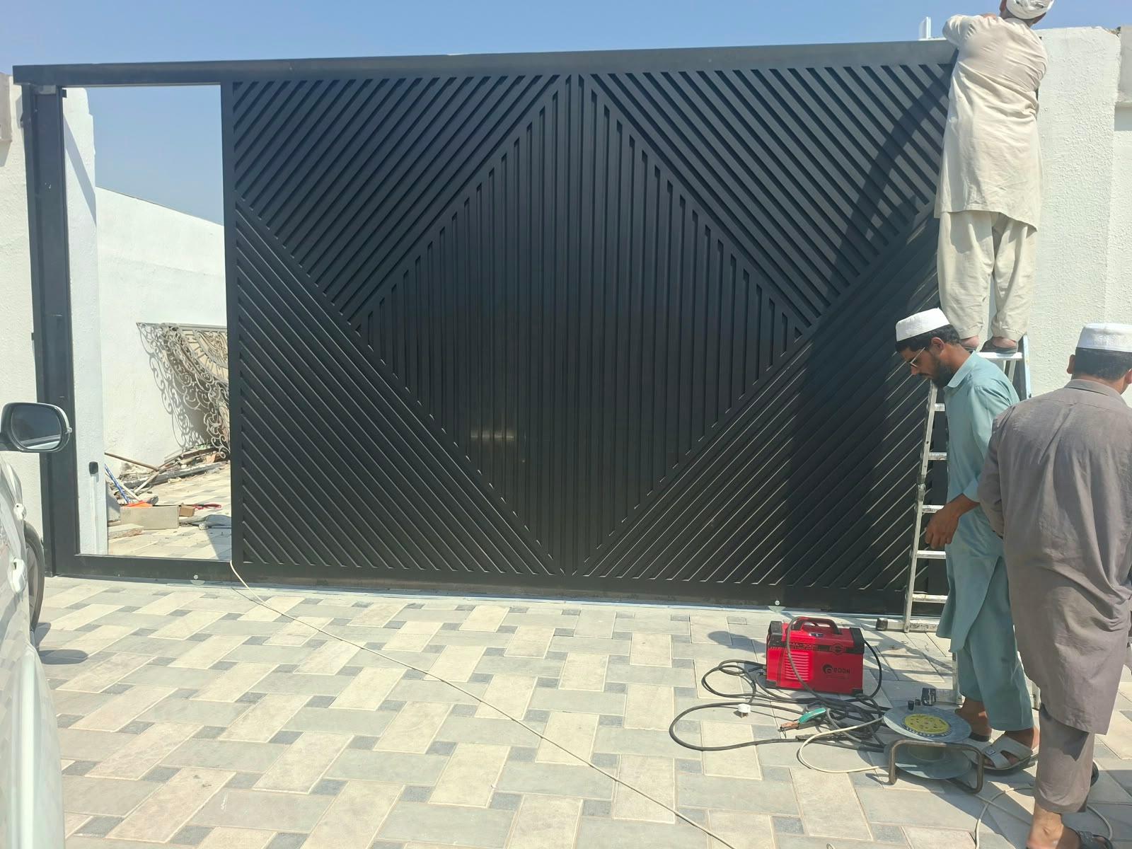 Crew installing a custom black geometric steel sliding gate