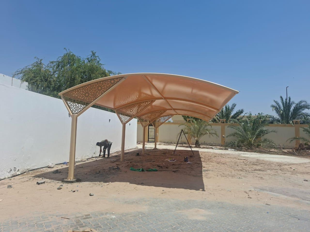 Tan cantilever parking shade with decorative geometric steel panels