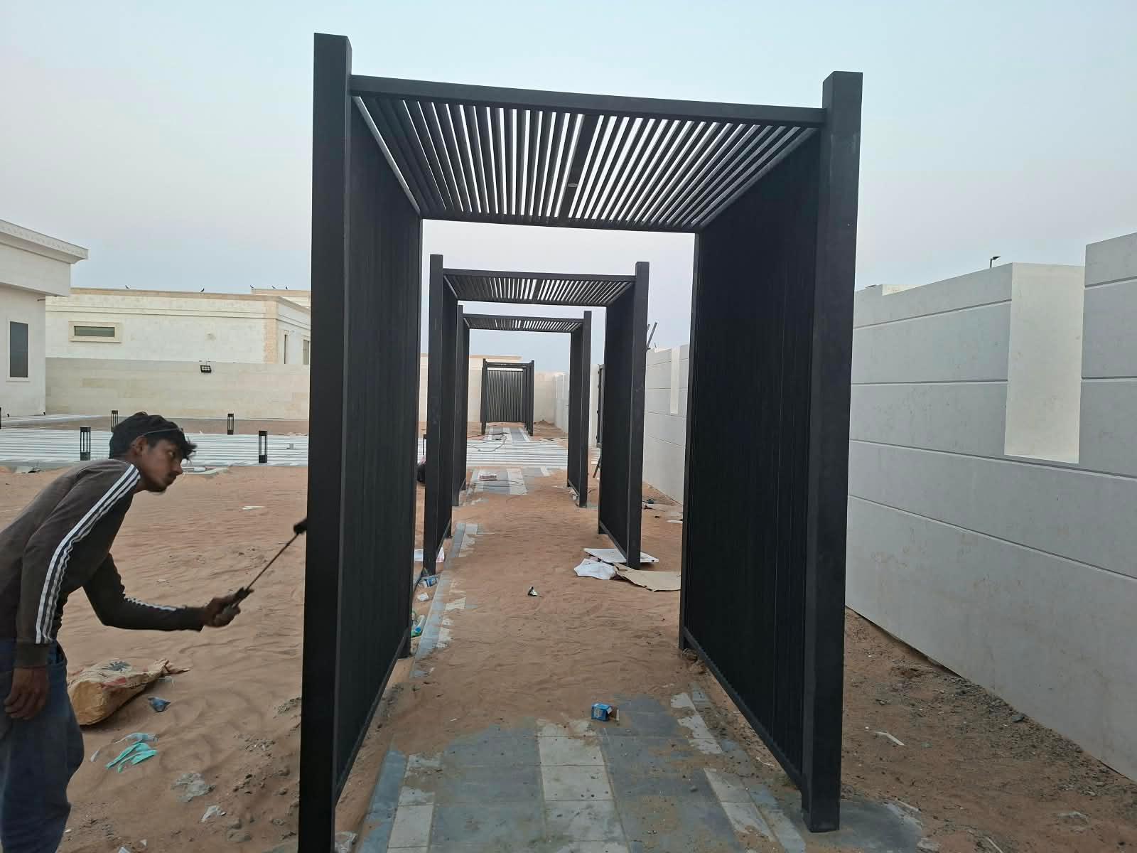 Row of black slatted walkway pergolas being finished on site