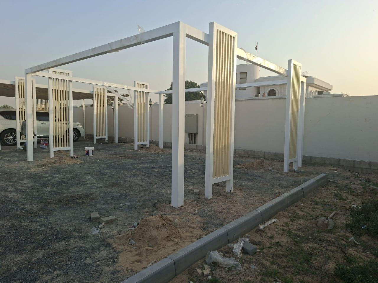 White steel frame with vertical slat screens being erected on site